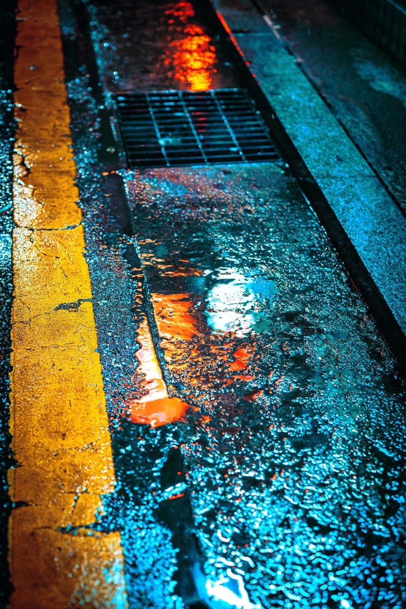 Una calle mojada con una línea amarilla y un semáforo en rojo.